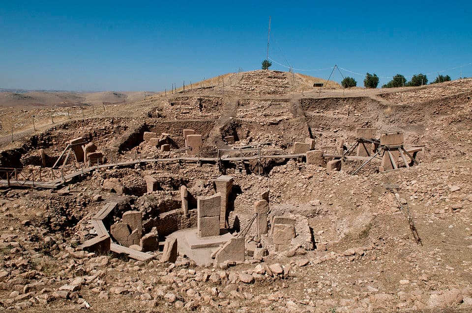 Aerial view of Göbekli Tepe's circular enclosures with T-shaped limestone pillars arranged in concentric rings, excavated from the surrounding hillside