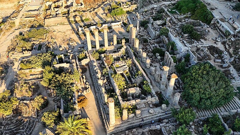 The ruined columns of the Temple of Apollo at Cyrene, Libya, standing against a blue Mediterranean sky.