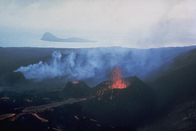 Lava flows issuing from three small cinder cones on Surtsey with the small island of Jolnir visible in the background, August 1966