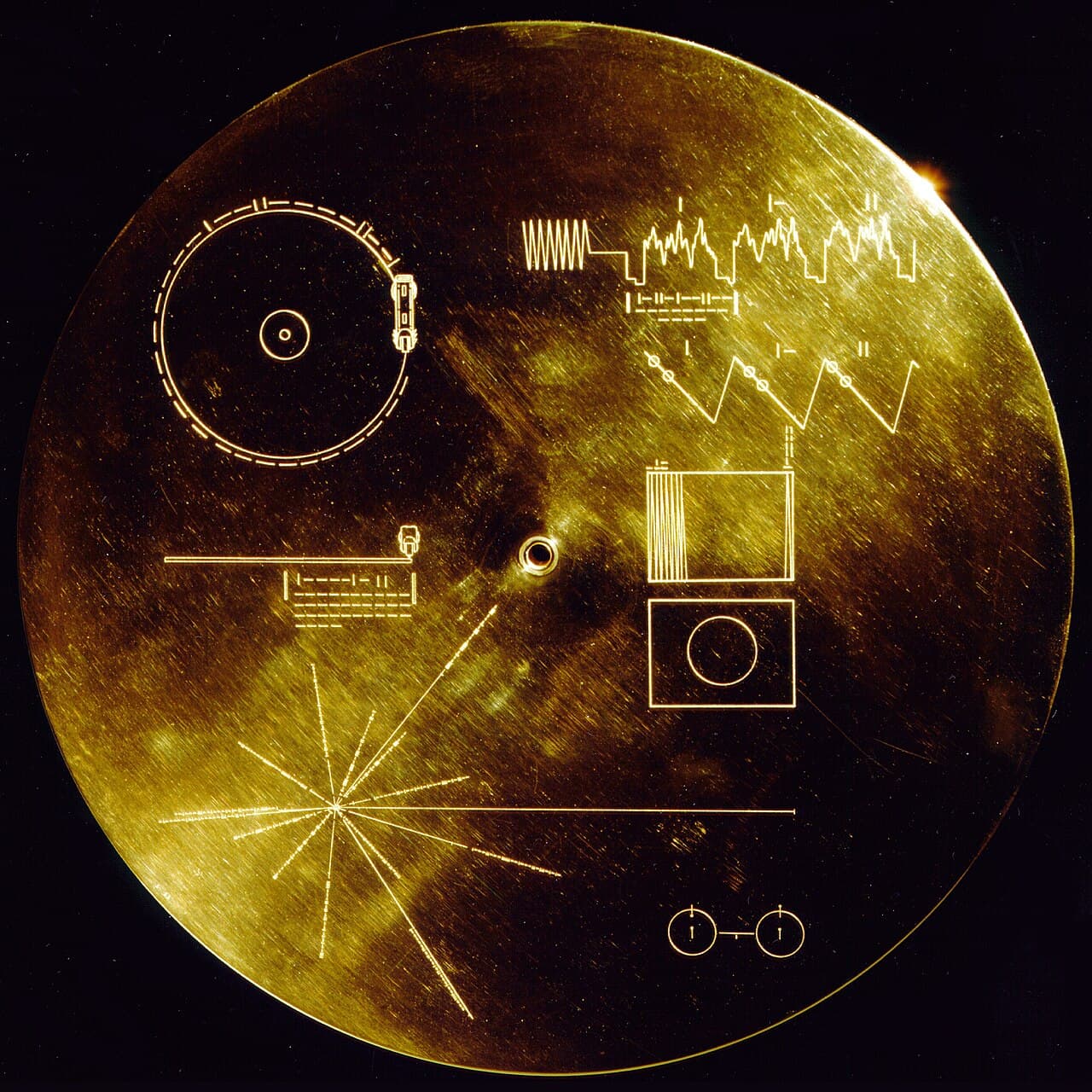 The engraved aluminum cover of the Voyager Golden Record, showing the pulsar map, the record playback diagram, and a reference to the hydrogen hyperfine transition.